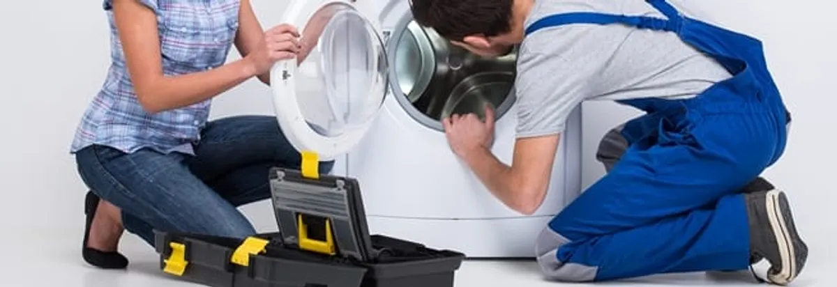 Washer repair technician inspecting a front-load washing machine with tools in New Orleans, LA