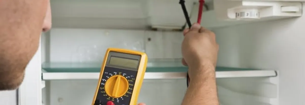 Refrigerator repair technician testing electrical components with a multimeter in New Orleans, LA