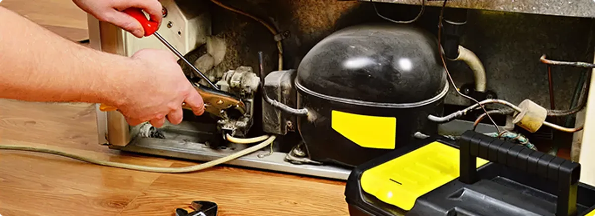Refrigerator repair technician fixing the compressor and wiring in New Orleans, LA