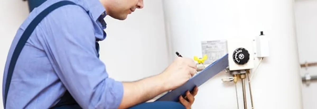 Water heater repair technician inspecting the unit and recording service notes in New Orleans, LA
